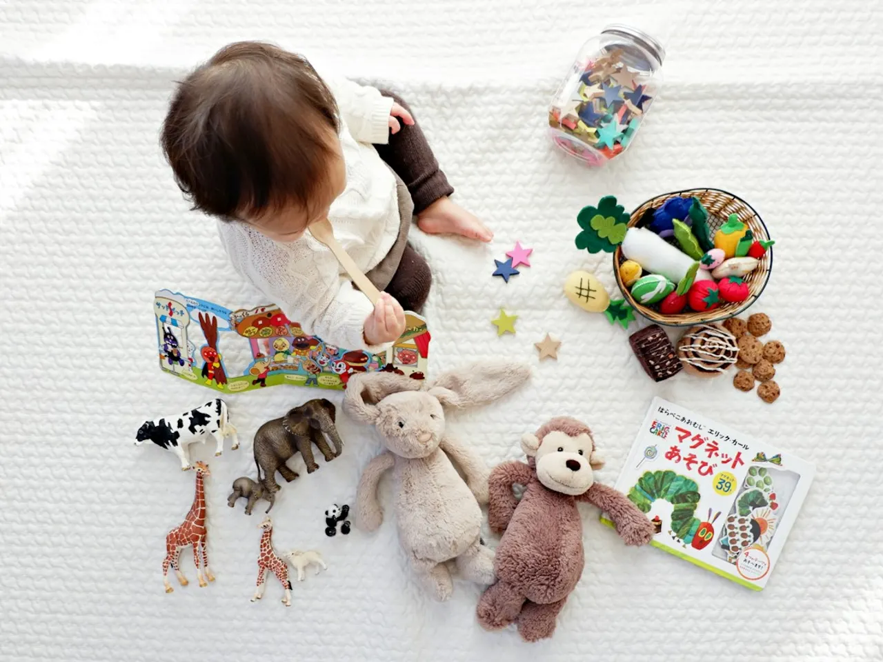親子品牌攝影示意照片：幼兒坐在地毯上，周圍擺放玩具、書本與布偶