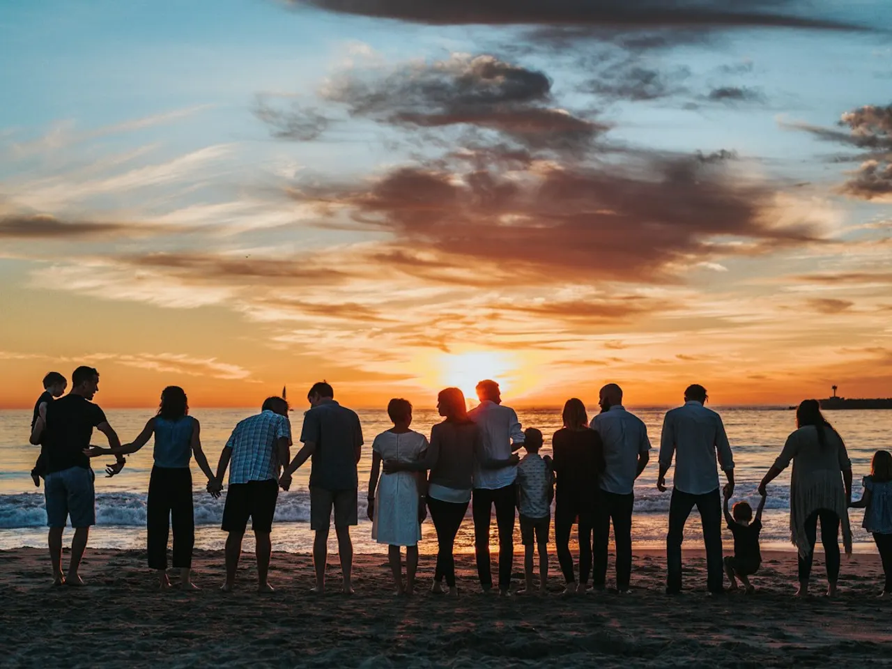 家庭寫真示意照片：大人與孩子牽手站在夕陽下的海灘